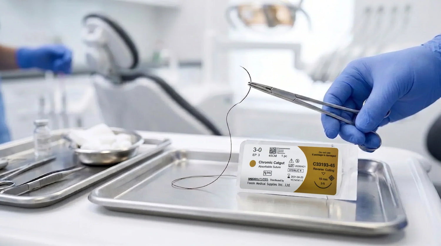 Gloved hand holding a needle holder with chromic catgut suture above a 4-0 sterile packet in a dental operating room